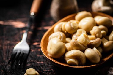Masadaki ahşap tabakta mantar turşusu. Karanlık bir arka plana karşı. Yüksek kalite fotoğraf