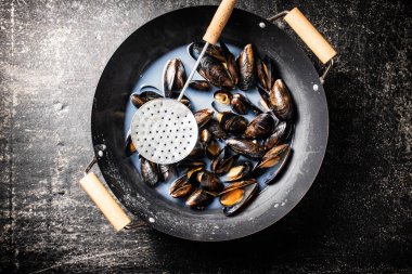 Masanın üzerinde bir tencere midye. Siyah bir arka planda. Üst Manzara. Yüksek kalite fotoğraf