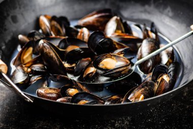 Midyeler bir tencere suda pişirilir. Siyah bir arka planda. Yüksek kalite fotoğraf