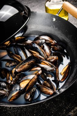 Midyeler bir tencere suda pişirilir. Siyah bir arka planda. Yüksek kalite fotoğraf
