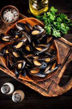 Maydanoz ve baharatlarla dolu bir tabakta haşlanmış midye. Ahşap bir arka planda. Yüksek kalite fotoğraf