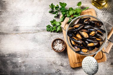 Maydanozlu kesme tahtasındaki süzgeçte midyeler. Gri bir arka planda. Yüksek kalite fotoğraf