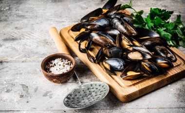 Tahta kesme tahtasının üzerinde haşlanmış midyeler. Gri bir arka planda. Yüksek kalite fotoğraf