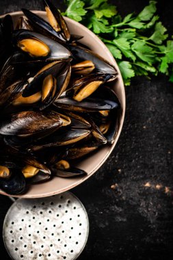 Maydanozlu bir kasede haşlanmış midye. Siyah bir arka planda. Yüksek kalite fotoğraf