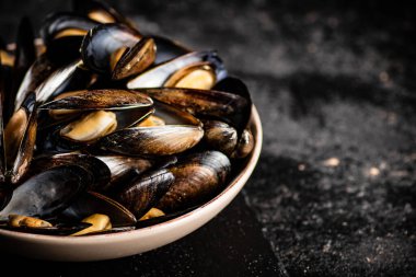 Masadaki kasede kaynamış midye. Siyah bir arka planda. Yüksek kalite fotoğraf