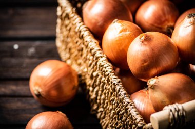 Masada bir sepet dolusu soğan var. Ahşap bir arka planda. Yüksek kalite fotoğraf