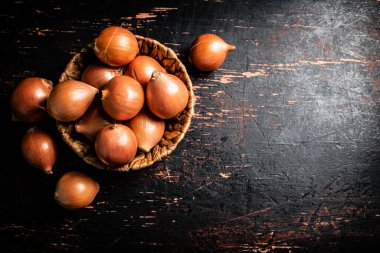 Masada bir sepet dolusu soğan var. Karanlık bir arka plana karşı. Yüksek kalite fotoğraf