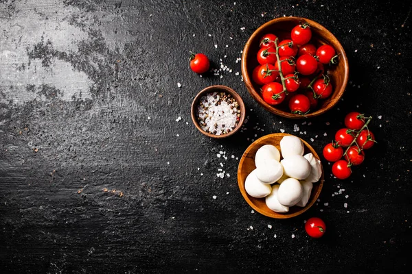 テーブルの上にボウルにトマトとスパイスとモッツァレラチーズ 暗い背景を背景に 高品質の写真 — ストック写真
