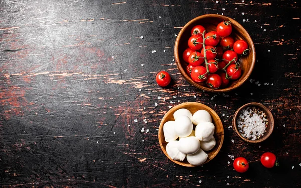 stock image Mozzarella cheese with tomatoes and spices in bowls on the table. Against a dark background. High quality photo