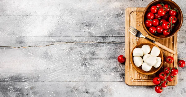 チェリートマトと木製のまな板上のモッツァレラチーズ 灰色の背景で 高品質の写真 — ストック写真