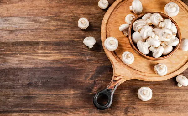 stock image Mushrooms in a bowl on a cutting board. On a wooden background. High quality photo