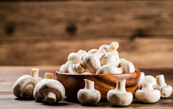 Деревянная тарелка со свежими грибами. На деревянном фоне. Высокое качество фото