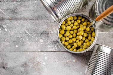 Konserve yeşil bezelyeli ve kaşıklı teneke kutuyu aç. Gri bir arka planda. Yüksek kalite fotoğraf