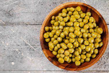 Konserve yeşil bezelyeli tam ahşap tabak. Gri bir arka planda. Yüksek kalite fotoğraf