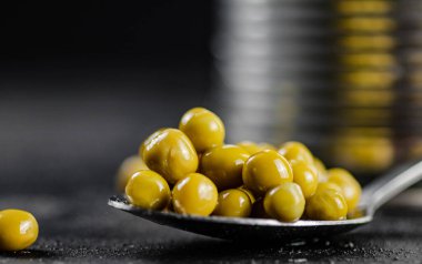 Bir kaşıkta konserve yeşil bezelye. Siyah bir arka planda. Yüksek kalite fotoğraf