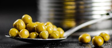 Bir kaşıkta konserve yeşil bezelye. Siyah bir arka planda. Yüksek kalite fotoğraf