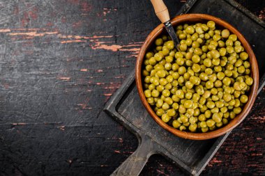 Ahşap bir kasede konserve yeşil bezelye. Siyah bir arka planda. Yüksek kalite fotoğraf