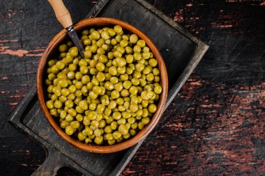 Ahşap bir kasede konserve yeşil bezelye. Siyah bir arka planda. Yüksek kalite fotoğraf