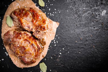 Kağıt üzerinde ızgara domuz eti ve defne yaprağı. Karanlık bir arka plana karşı. Yüksek kalite fotoğraf