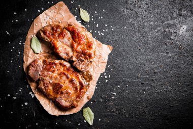 Kağıt üzerinde ızgara domuz eti ve defne yaprağı. Karanlık bir arka plana karşı. Yüksek kalite fotoğraf