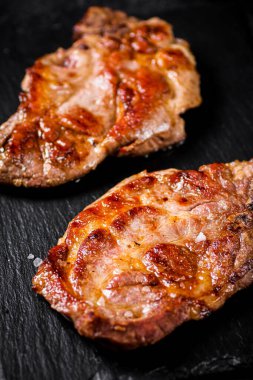 Taş bir tahtanın üzerinde leziz ızgara domuz bifteği. Siyah bir arka planda. Yüksek kalite fotoğraf