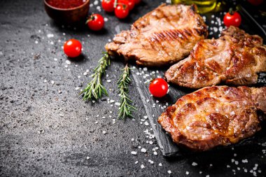 Kızarmış domuz bifteği, kiraz domatesli ve biberiyeli. Siyah bir arka planda. Yüksek kalite fotoğraf