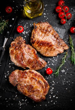Kızarmış domuz bifteği, kiraz domatesli ve biberiyeli. Siyah bir arka planda. Yüksek kalite fotoğraf