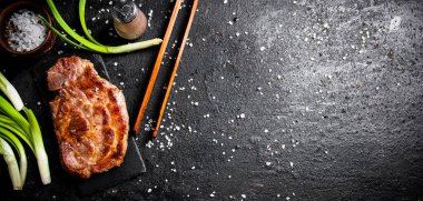 Taze soğan ve baharatla ızgara domuz bifteği. Siyah bir arka planda. Yüksek kalite fotoğraf