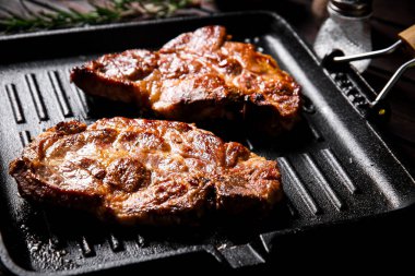 Biberiyeyle ızgarada pişirilmiş domuz bifteği. Koyu ahşap bir arka planda. Yüksek kalite fotoğraf