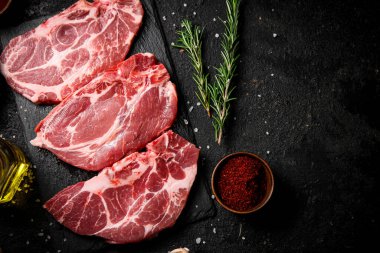 Taş bir tahtanın üzerinde çiğ domuz eti. Siyah bir arka planda. Yüksek kalite fotoğraf