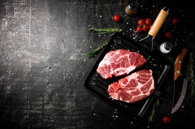 Kızartma tavasında çiğ domuz eti, defne yaprakları ve biberiyeli. Karanlık bir arka plana karşı. Yüksek kalite fotoğraf