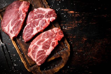 Tahta kesme tahtasında çiğ domuz eti. Karanlık bir arka plana karşı. Yüksek kalite fotoğraf