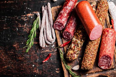 Biberiyeli dilimleme tahtasındaki farklı salam türleri. Karanlık bir arka plana karşı. Yüksek kalite fotoğraf