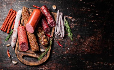 Biberiyeli dilimleme tahtasındaki farklı salam türleri. Karanlık bir arka plana karşı. Yüksek kalite fotoğraf