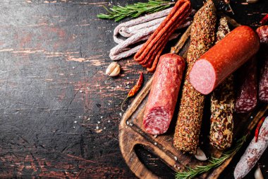 Biberiyeli dilimleme tahtasındaki farklı salam türleri. Karanlık bir arka plana karşı. Yüksek kalite fotoğraf