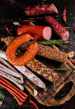 Biberiyeli dilimleme tahtasındaki farklı salam türleri. Karanlık bir arka plana karşı. Yüksek kalite fotoğraf