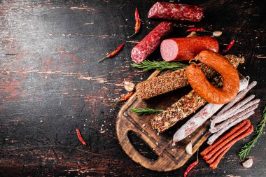 Biberiyeli dilimleme tahtasındaki farklı salam türleri. Karanlık bir arka plana karşı. Yüksek kalite fotoğraf