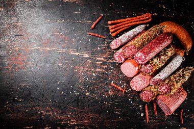Masada kurutulmuş kırmızı biberli çeşitli salamlar. Karanlık bir arka plana karşı. Yüksek kalite fotoğraf