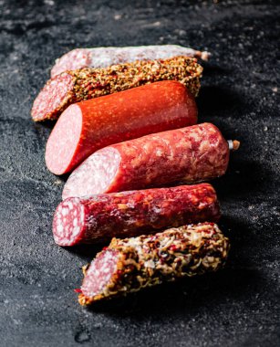 Masanın üzerinde çeşitli salam parçaları var. Siyah bir arka planda. Yüksek kalite fotoğraf