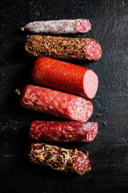 Masanın üzerinde çeşitli salam parçaları var. Siyah bir arka planda. Yüksek kalite fotoğraf