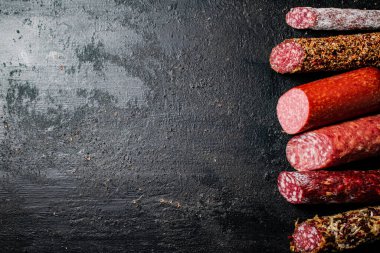 Masanın üzerinde çeşitli salam parçaları var. Siyah bir arka planda. Yüksek kalite fotoğraf