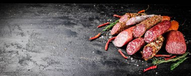 Biberiyeli ve kurutulmuş kırmızı biberli farklı türde salam sosisi. Siyah bir arka planda. Yüksek kalite fotoğraf