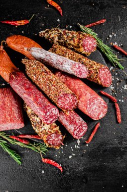 Biberiyeli ve kurutulmuş kırmızı biberli farklı türde salam sosisi. Siyah bir arka planda. Yüksek kalite fotoğraf