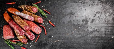 Biberiyeli ve kurutulmuş kırmızı biberli farklı türde salam sosisi. Siyah bir arka planda. Yüksek kalite fotoğraf