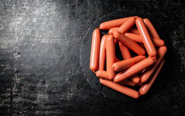 Taş bir tahtanın üzerinde bir sürü sosis kaynatılmış. Siyah bir arka planda. Yüksek kalite fotoğraf