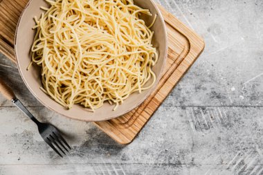 Kesme tahtasında haşlanmış spagetti ile dolu bir kâse. Gri bir arka planda. Yüksek kalite fotoğraf