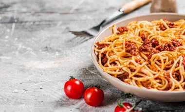 Masada vişneli domatesli spagetti bolonez. Gri bir arka planda. Yüksek kalite fotoğraf