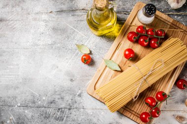 Tahta kesme tahtasının üzerinde domatesli spagetti. Gri bir arka planda. Yüksek kalite fotoğraf
