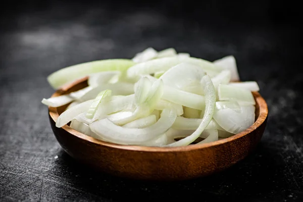 stock image Chopped onions in a wooden plate. On a black background. High quality photo