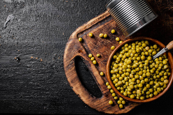Консервированный зеленый горох в деревянной чаше. На черном фоне. Высокое качество фото